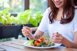 The smiling woman enjoys eating a salmon salad. To lose weight and diet, eat foods that are beneficial to the body. Weight loss concept. photo