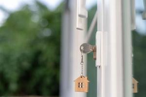 la llave del propietario para desbloquear la casa está enchufada en la puerta. casa de segunda mano en alquiler y venta. llavero está soplando en el viento. hipoteca para casa nueva, compra, venta, renovación, inversión, propietario, patrimonio foto