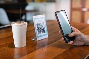 el hombre usa un teléfono inteligente para escanear el código qr para pagar en un café restaurante con un pago digital sin efectivo. elige menú y ordena acumula descuento. billetera electrónica, tecnología, pago en línea, tarjeta de crédito, aplicación bancaria foto