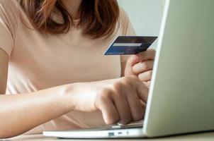 Young woman use credit card for shopping payment online on laptop computer application or website. E-commerce and online shopping concept. Stay home and Buy products online. photo