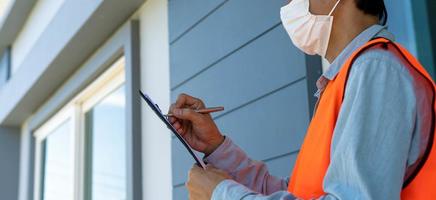 Inspectors or engineers are wearing an anti-virus mask and checking the building structure and the requirements of the wall paint. After the renovation is completed photo