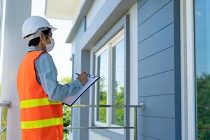 el inspector o ingeniero está revisando e inspeccionando el edificio o la casa usando una lista de verificación. ingenieros y arquitectos trabajan en la construcción de la casa antes de entregársela al propietario. foto