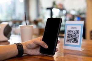 el hombre usa un teléfono inteligente para escanear el código qr para pagar en un café restaurante con un pago digital sin efectivo. elige menú y ordena acumula descuento. billetera electrónica, tecnología, pago en línea, tarjeta de crédito, aplicación bancaria foto