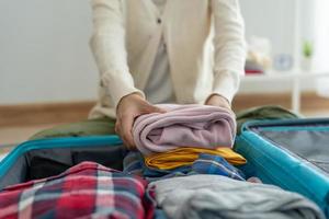 Travel bags for vacation trips. A young woman prepares clothes and personal items to put in her suitcase. Pack your bags before traveling photo