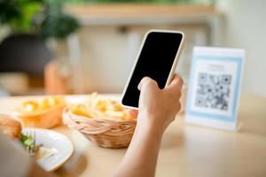 la gente usa el teléfono inteligente para escanear el código qr en el café. el restaurante construyó un sistema de pago digital sin efectivo. pago con código qr, billetera electrónica, tecnología de efectivo, pago en línea foto