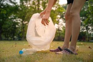 salvar mundo voluntario recoger basura en el parque. la gente recolecta botellas de plástico difíciles de descomponer para evitar daños a los animales. día de la tierra, día del medio ambiente. ecologizar el planeta y reducir el calentamiento global foto