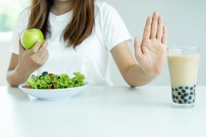 las mujeres rechazan la comida chatarra o los alimentos poco saludables como las donas y eligen alimentos saludables como las manzanas verdes y las ensaladas. concepto de ayuno y buena salud. foto