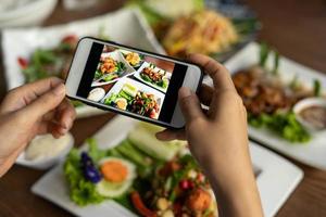 mujer toma una foto de una comida en la mesa después de pedir comida en línea para comer en casa. fotografía y uso de conceptos de teléfono