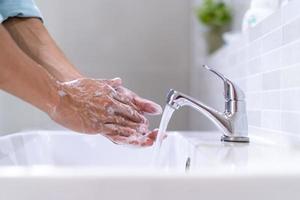 Men washing hands with soap and clean water in front of the bathroom sink to prevent the spread of germs. Washing hands with soap. photo