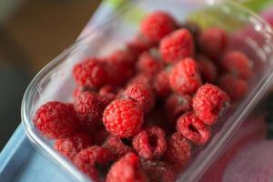 Close up of a plastic recipient with raspberries in bad condition photo