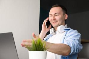 Happy asian man talking on the phone and pointing at laptop screen.Work from home etc photo