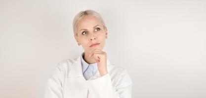 Closeup of young female doctor thinking and looking at empty space. Banner with place for text photo