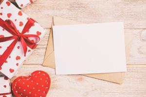 Envelope Mail with Red Heart and gift box over Orange Wooden Background. Valentine Day Card, Love or Wedding Greeting Concept photo