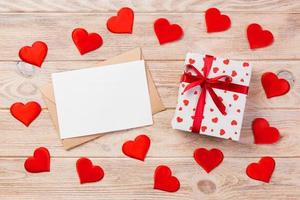 Envelope Mail with Red Heart and gift box over Orange Wooden Background. Valentine Day Card, Love or Wedding Greeting Concept photo