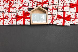 Top view of gift boxes with red hearts and wooden calendar on colorful background. The fourteenth of february. St Valentine's day concept with copy space photo