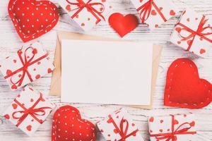 correo de sobre con corazón rojo y caja de regalo sobre fondo blanco de madera. tarjeta de san valentín, amor o concepto de saludo de boda foto