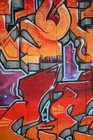 A fragment of detailed graffiti of a drawing made with aerosol paints on a wall of concrete tiles. Background image of street art in warm red color tones photo