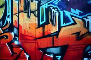 A fragment of detailed graffiti of a drawing made with aerosol paints on a wall of concrete tiles. Background image of street art in warm red color tones photo