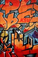 A fragment of detailed graffiti of a drawing made with aerosol paints on a wall of concrete tiles. Background image of street art in warm red color tones photo