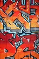 A fragment of detailed graffiti of a drawing made with aerosol paints on a wall of concrete tiles. Background image of street art in warm red color tones photo