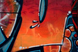 A fragment of detailed graffiti of a drawing made with aerosol paints on a wall of concrete tiles. Background image of street art in warm red color tones photo