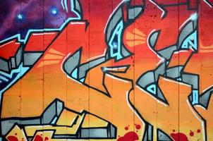 A fragment of detailed graffiti of a drawing made with aerosol paints on a wall of concrete tiles. Background image of street art in warm red color tones photo