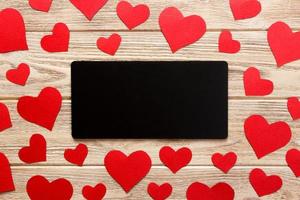 Card to Valentine's Day. Red hearts and empty letter on wooden background. Flat lay composition with copy space photo