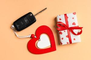 Top view of gift box, car key and wooden heart on colorful background. Luxury present for Valentine's day photo