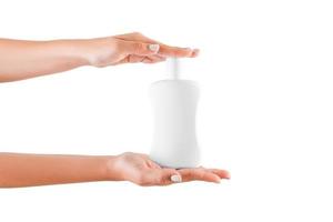 mano femenina sosteniendo una botella de crema de loción aislada. Chica dar productos cosméticos sobre fondo blanco. foto