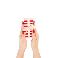 Woman hands give wrapped Christmas or other holiday handmade present in red paper with gold ribbon. Isolated on white background, top view. thanksgiving Gift box concept photo