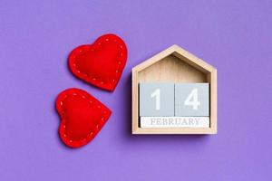 Top view of wooden calendar and textile hearts on colorful background. The fourteenth of February. Valentine's day concept photo