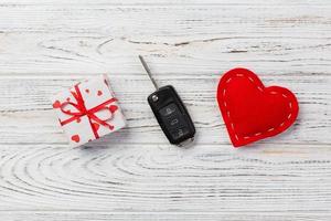 Valentine or other holiday handmade present in paper with red hearts, car keys and gifts box in holiday wrapper. box gift on white wooden table top view with copy space, empty space for design photo