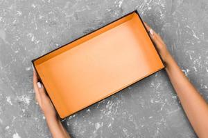 Female hands with open empty box on gray background photo