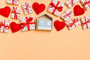 Top view of gift boxes, wooden calendar and red textile hearts on colorful background. The fourteenth of february. St Valentine's day concept with copy space photo