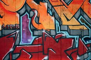 A fragment of detailed graffiti of a drawing made with aerosol paints on a wall of concrete tiles. Background image of street art in warm red color tones photo