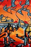 A fragment of detailed graffiti of a drawing made with aerosol paints on a wall of concrete tiles. Background image of street art in warm red color tones photo