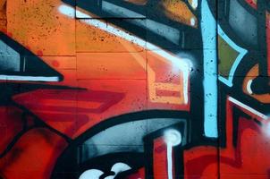 A fragment of detailed graffiti of a drawing made with aerosol paints on a wall of concrete tiles. Background image of street art in warm red color tones photo