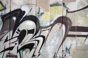 A fragment of detailed graffiti of a drawing made with aerosol paints on a wall of concrete tiles. Background image of street art in brown and cream tones photo