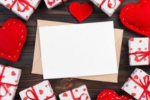 correo de sobre con corazón rojo y caja de regalo sobre fondo de madera oscura. tarjeta de san valentín, amor o concepto de saludo de boda foto