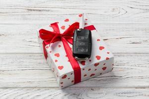 Valentine or other holiday handmade present in paper with red hearts, car keys and gifts box in holiday wrapper. box gift on white wooden table top view with copy space, empty space for design photo
