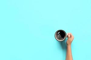 Minimalistic style woman hand holding a mug of coffee on background. Flat lay, top view photo