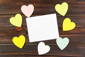 Empty paper over wooden background with colorful heart on valentines day photo