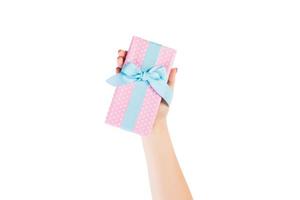 Woman hands give wrapped Christmas or other holiday handmade present in pink paper with blue ribbon. Isolated on white background, top view. thanksgiving Gift box concept photo