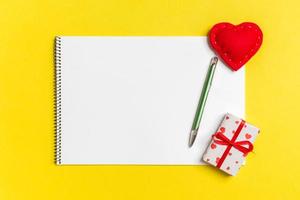 Top view of craft notebook surrounded with hearts and gift boxes on colorful background. Valentine's day photo