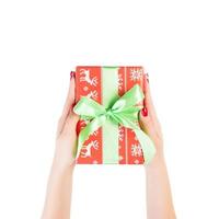 Woman hands give wrapped Christmas or other holiday handmade present in red paper with green ribbon. Isolated on white background, top view. thanksgiving Gift box concept photo