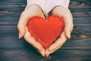 A woman holds a red heart in her hands. Love concept toned, vintage photo