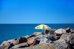 Lonely umbrella standing in stones on a wild beach photo