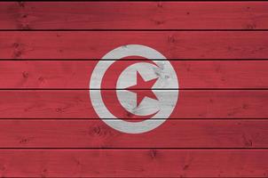 bandera de túnez representada en colores de pintura brillante en una pared de madera vieja. banner texturizado sobre fondo áspero foto