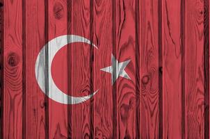 Turkey flag depicted in bright paint colors on old wooden wall. Textured banner on rough background photo