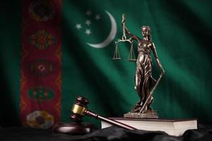 Turkmenistan flag with statue of lady justice, constitution and judge hammer on black drapery. Concept of judgement and guilt photo